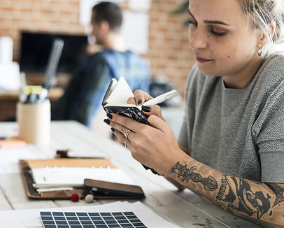 Woman with tattoos taking notes and planning time in a calendar 