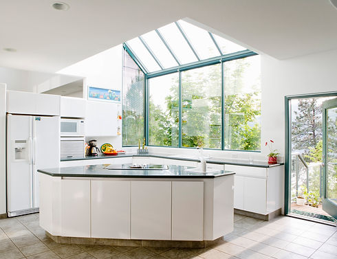 Modern kitchen with large skylights and windows revealing lush green trees