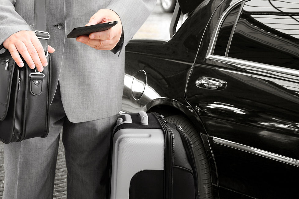Businessman in a suit holding a tablet next to an executive transport car