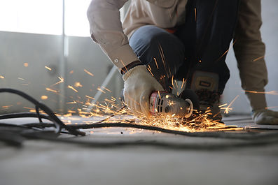 A builder operating a metal grinder tool at a commercial premises in Cardiff, South Wales