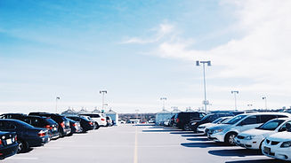 A row of parked cars under a bright, clear sky in a spacious parking lot