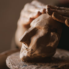 Sculptor's hands shaping clay head bust
