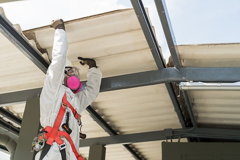 Worker wearing full body protective clothing while working with the asbestos roof. Hazardo