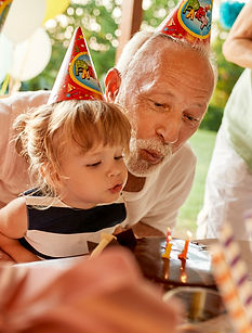 image of grandfather and granddaughter blowing out candles at birthday party