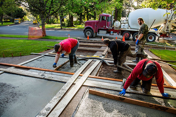 Concrete truck and construction crew pouring concrete in a residential driveway