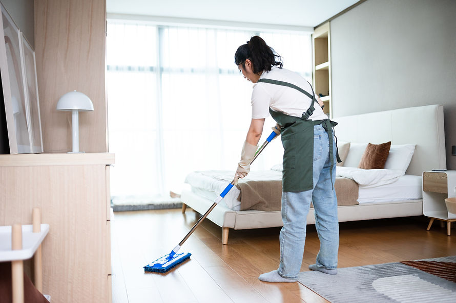 A female cleaner vacuuming a bright bedroom