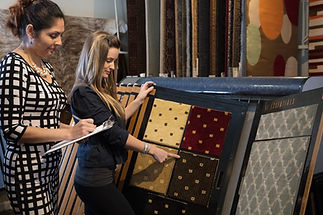 Woman browsing through textured carpet and wooden flooring samples in a home interiors showroom