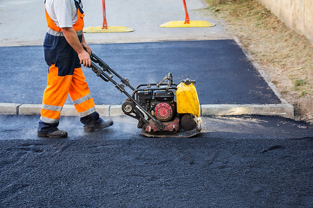 Worker use vibratory plate compactor compacting asphalt at road repair