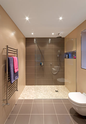 Modern bathroom with a wet room, brown tiled walls, and a towel rack with towels