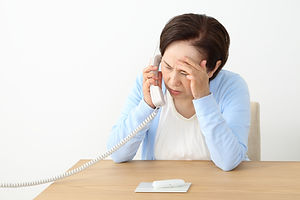 電話をしながら頭を抱えるシニア女性