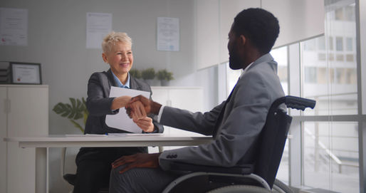 duas pessoas dando a mão após uma entrevista de emprego, em um escritório corporativo.