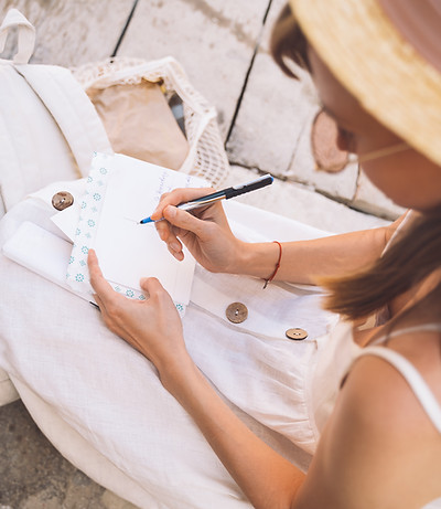 YOUNG, LADY WEARING A WIDE BRIM HAT writing in meditation journal