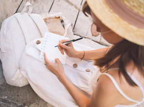 Woman in a hat writes her August content ideas on a piece of paper to create her social media content calendar.
