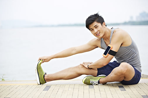 Young Man Performing Sciatic Nerve Stretches while Sitting on a Lake Side Dock
