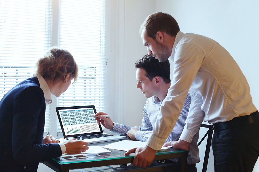 Business professionals reviewing financial spreadsheets displayed on a computer screen