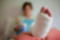 A close-up of a person's leg with a white cast on their foot, resting on a bed
