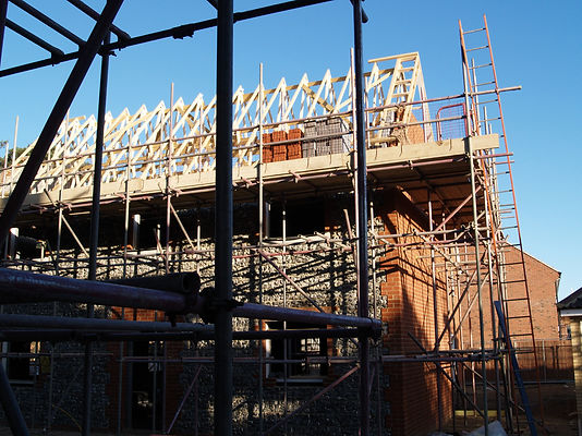 Close-up view of scaffolding framework surrounding timber roof joists on a Newport build