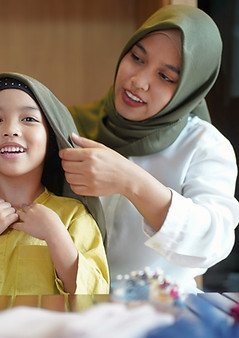 A woman putting a hijab on the girl
