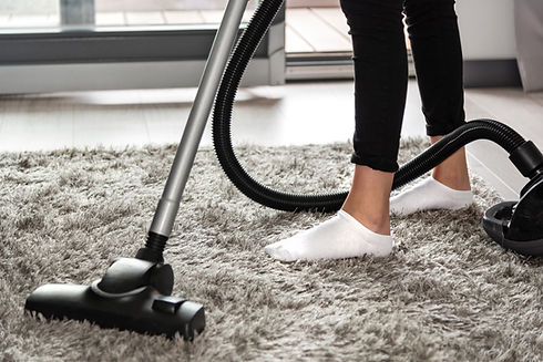 Low Section Of Woman Using Vacuum Cleaner On Rug