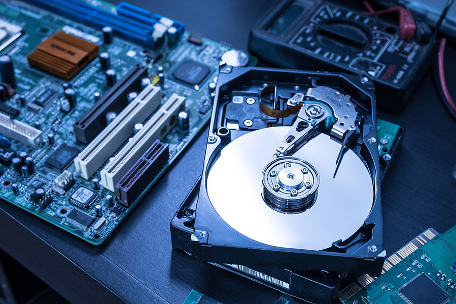 Open hard drive and computer motherboard on a table, with cables and components visible
