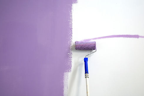 Close-up of a paint roller painting a lilac wall