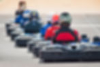 Group of drivers lined up in go-karts on a racetrack, ready for a competitive outdoor session in Budapest.