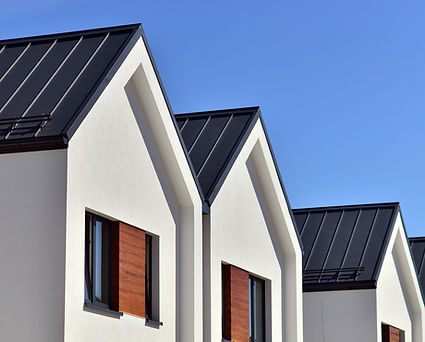 Outside view oif the front of three white houses in a row.