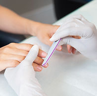 Manicure in progress with nail filing by a technician