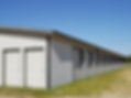 Modern storage unit facility featuring dark grey profile cladding and multiple roller shutter doors
