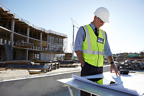 Architect looking at building plans laid out on a table in front of a new office