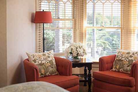 Light filled corner of bedroom with red chairs and white flowers