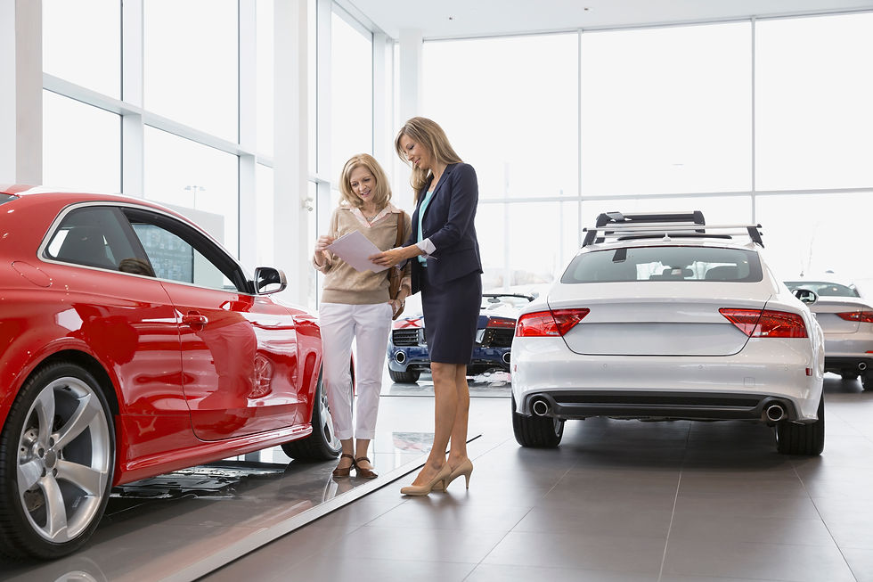Person reviewing papers with a car salesperson in a bright dealership showroom