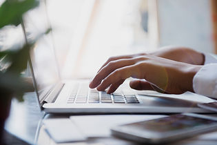 Hands typing on a laptop keyboard in a bright workspace