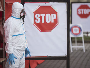 A man in a protective suit standing next to a stop sign.