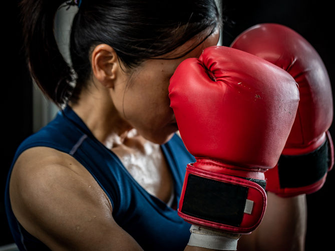 A woman with boxing gloves hiding her face