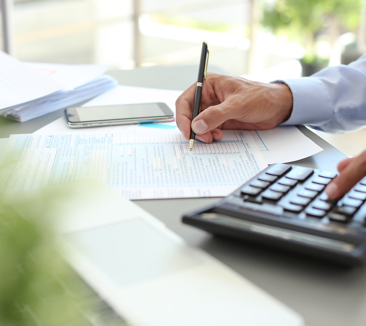 Person using a calculator and pen to estimate interstate moving costs based on weight and distance
