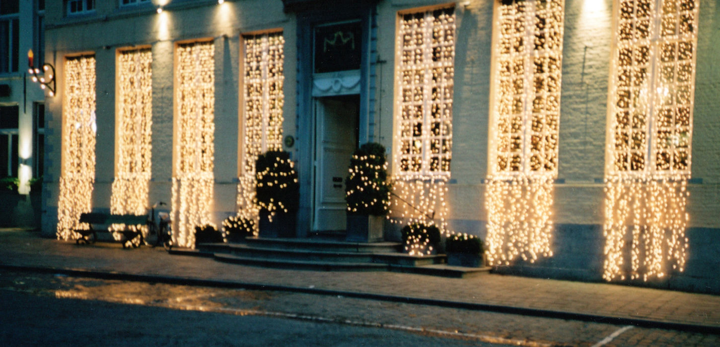 Building facade with large windows draped in fairy lights at night