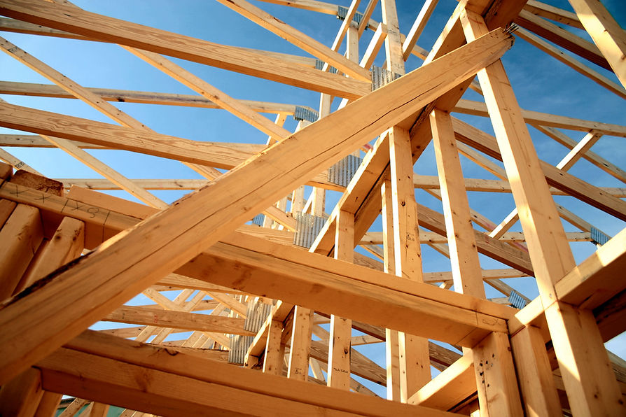 Construction view of a wooden frame structure against a bright blue sky