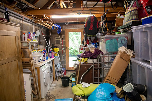 A cluttered garage or utility room filled with tools, laundry appliances, and various stored household items
