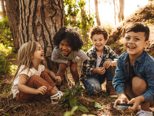 A diverse group of four kids smiling while playing outside.