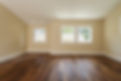 Polished dark wooden floor in an empty bedroom with cream walls and natural light from windows