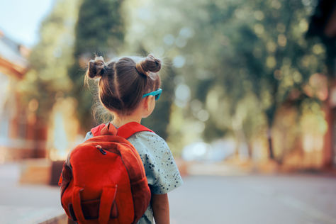 Little girl wearing a red back pack, ready for school