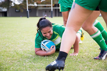 A rugby player in green holding a rugby ball during a game