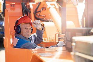 Worker on forklift moving wood pallet stacks in pallet yard.
