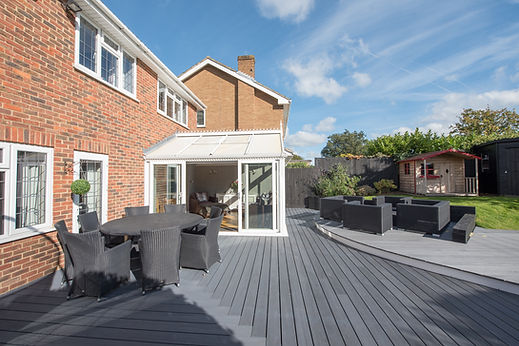 A general exterior view of a home showing the back garden with grey decking area