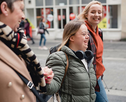 Young women walking outside including a woman with Down syndrome wearing headphones