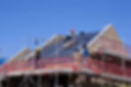Builders roofers working on scaffolding on roof completing construction of new house uk