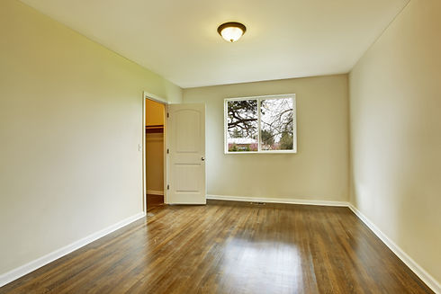 An empty room with hardwood flooring and a walk-in closet