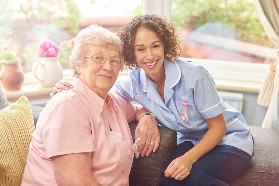 a senior woman in her home with her home carer . The nurse has her arm around her patient
