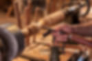 A craftsman turning a wooden table leg on a lathe, shaping it with a chisel